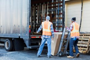 two professional movers in jackets and warm hats loading a moving truck in the winter