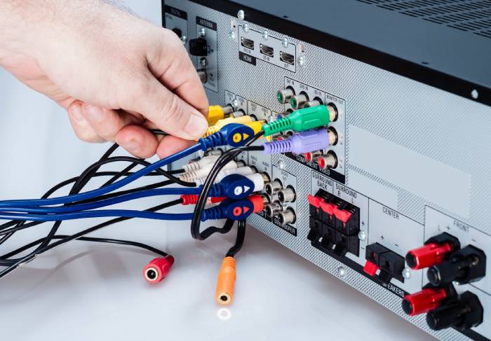 Photo of hand connecting cables to an AV Receiver, on a white background