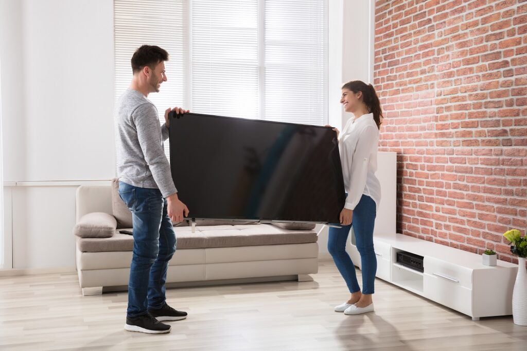 Couple Holding Television At Home